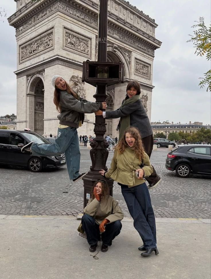 Quatre amies posent autour d'un lampadaire devant l'Arc de Triomphe.